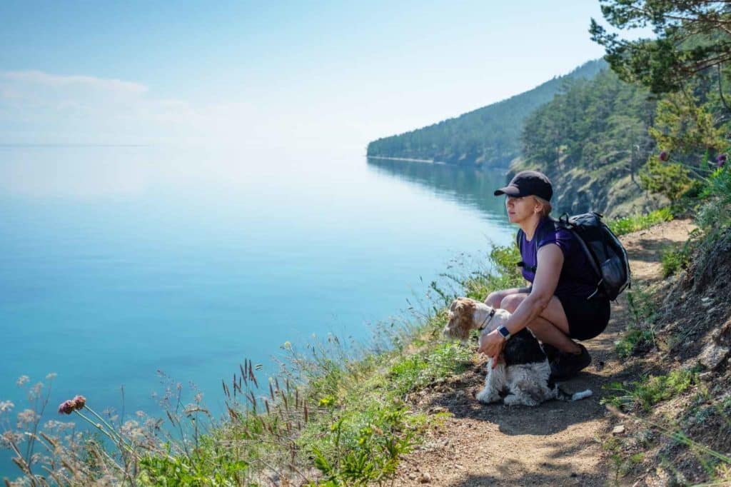 Frau schaut über einen See mit Hund